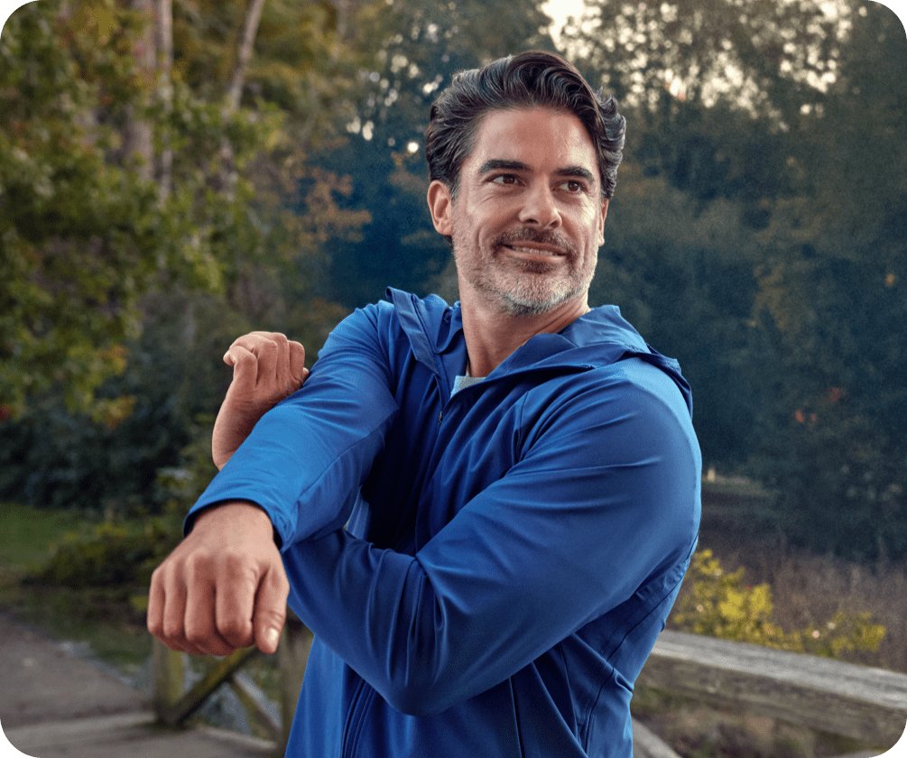 Two people are in a park while a man is stretching