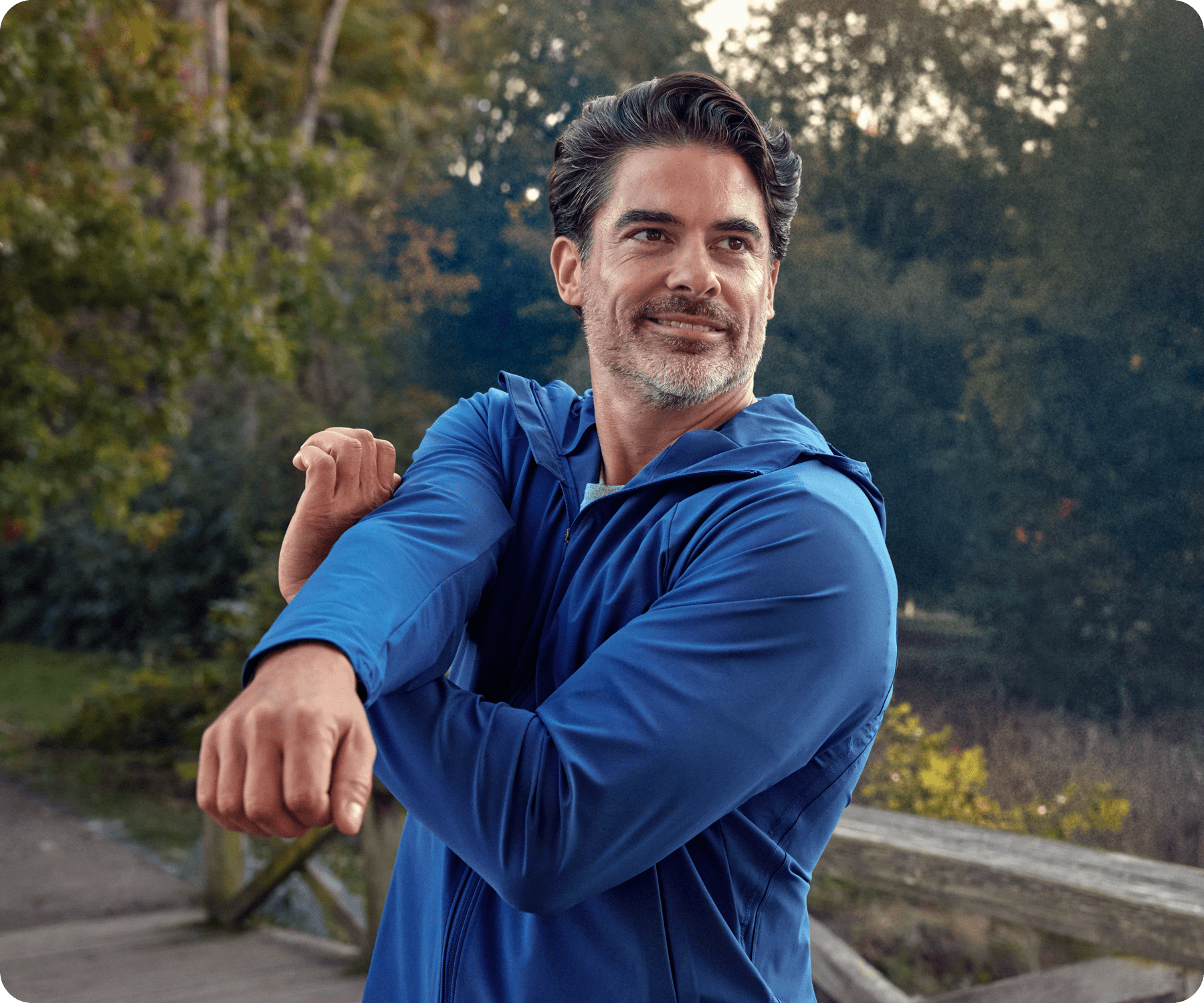 Two people are in a park while a man is stretching