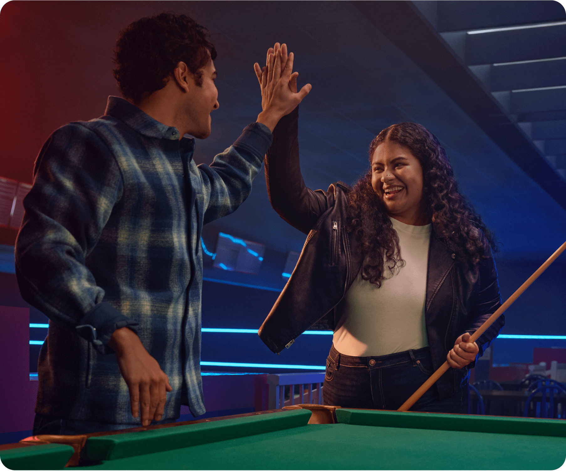 A couple is in a pool hall high fiving.