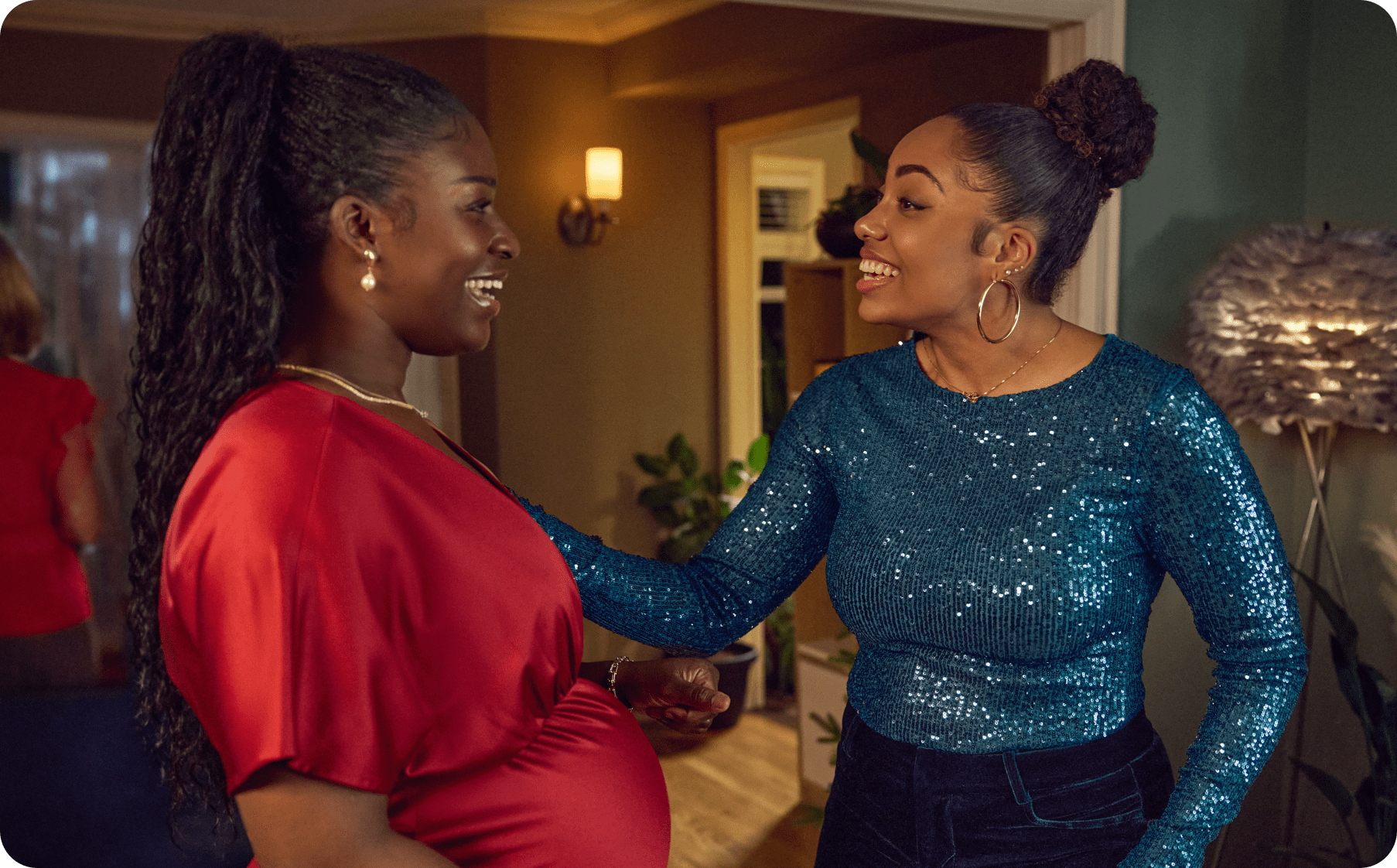 Female friends are smiling speaking in a house.