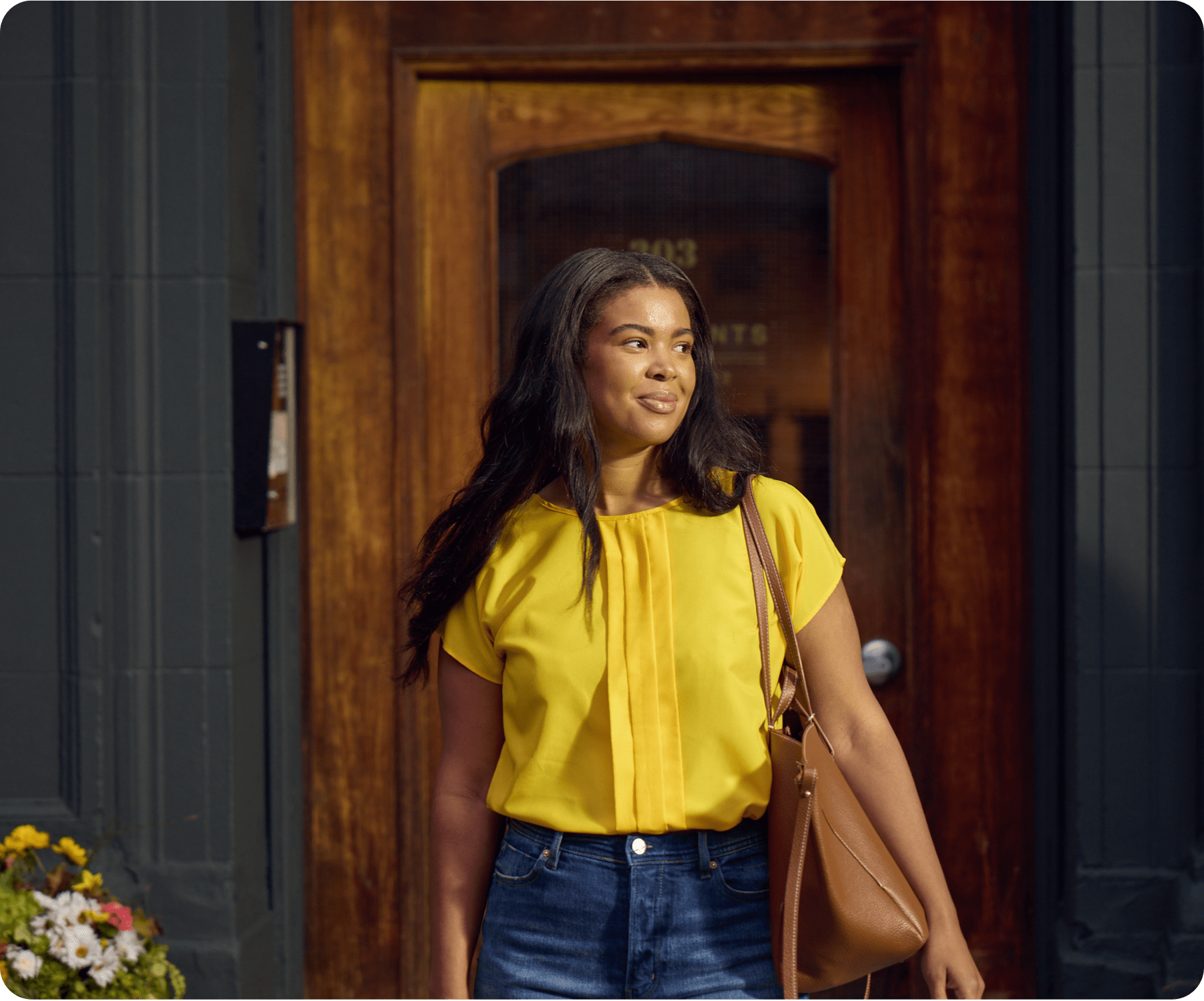 A woman is smiling standing outside of an apartment.