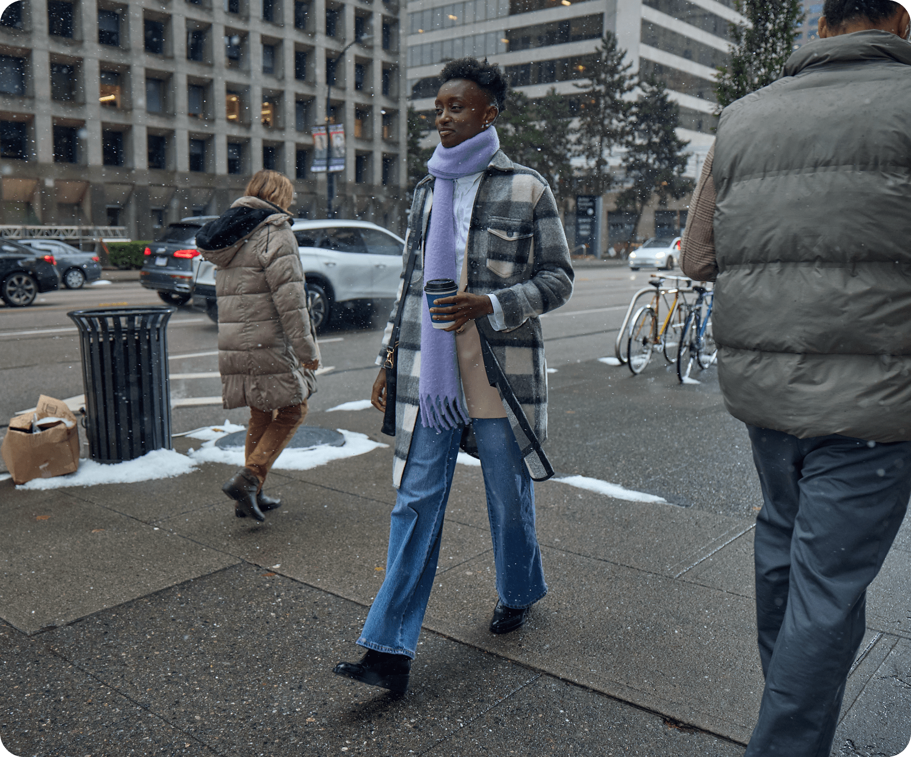 A woman is holding coffee walking down the street 